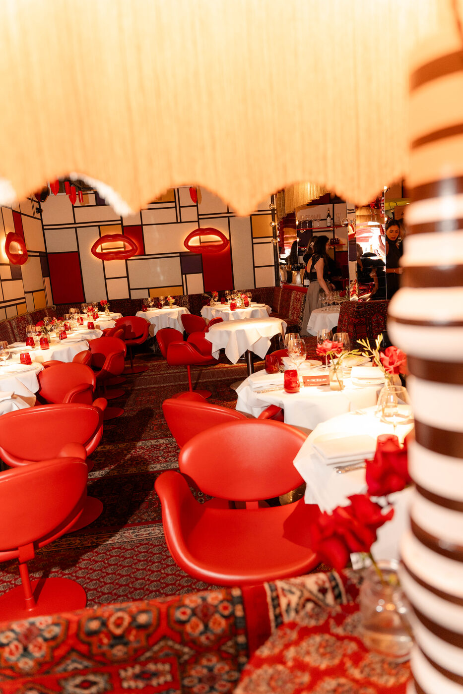 Dining room at Bisous, Amsterdam — red leather chairs, candlelit tables and Mondrian-patterned wall panels